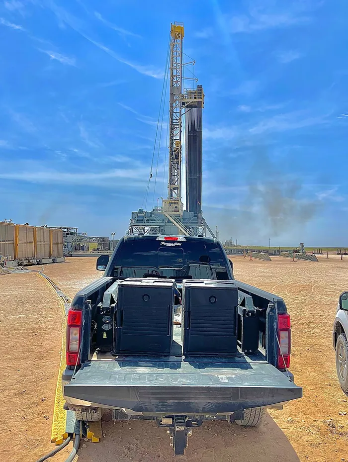 A drilling rig above a pickup loaded with MaMa E's catering boxes