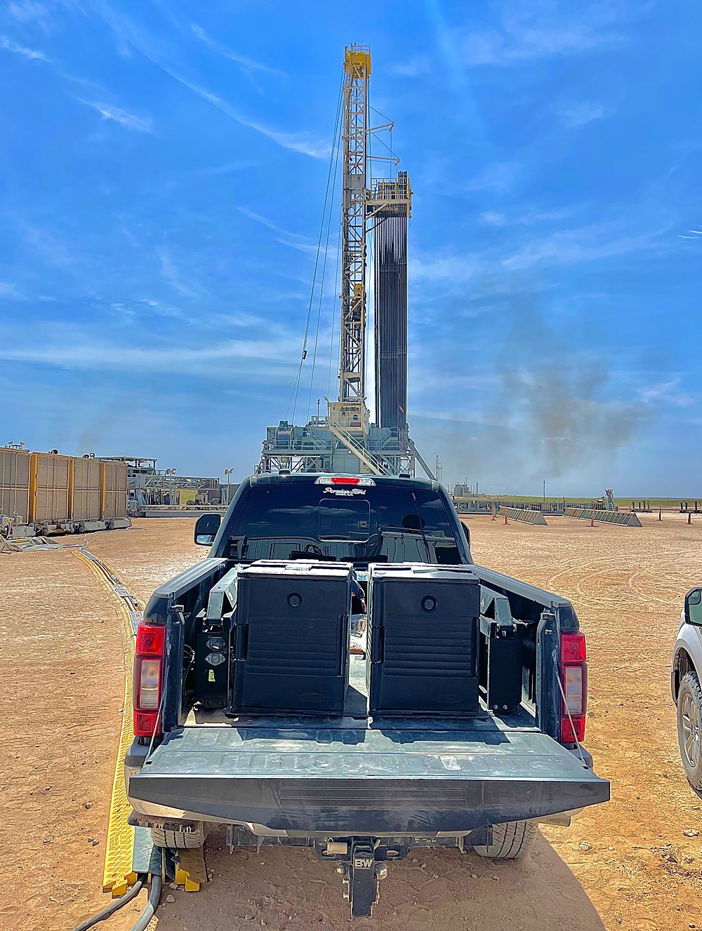 A drilling rig above a pickup loaded with MaMa E's catering boxes