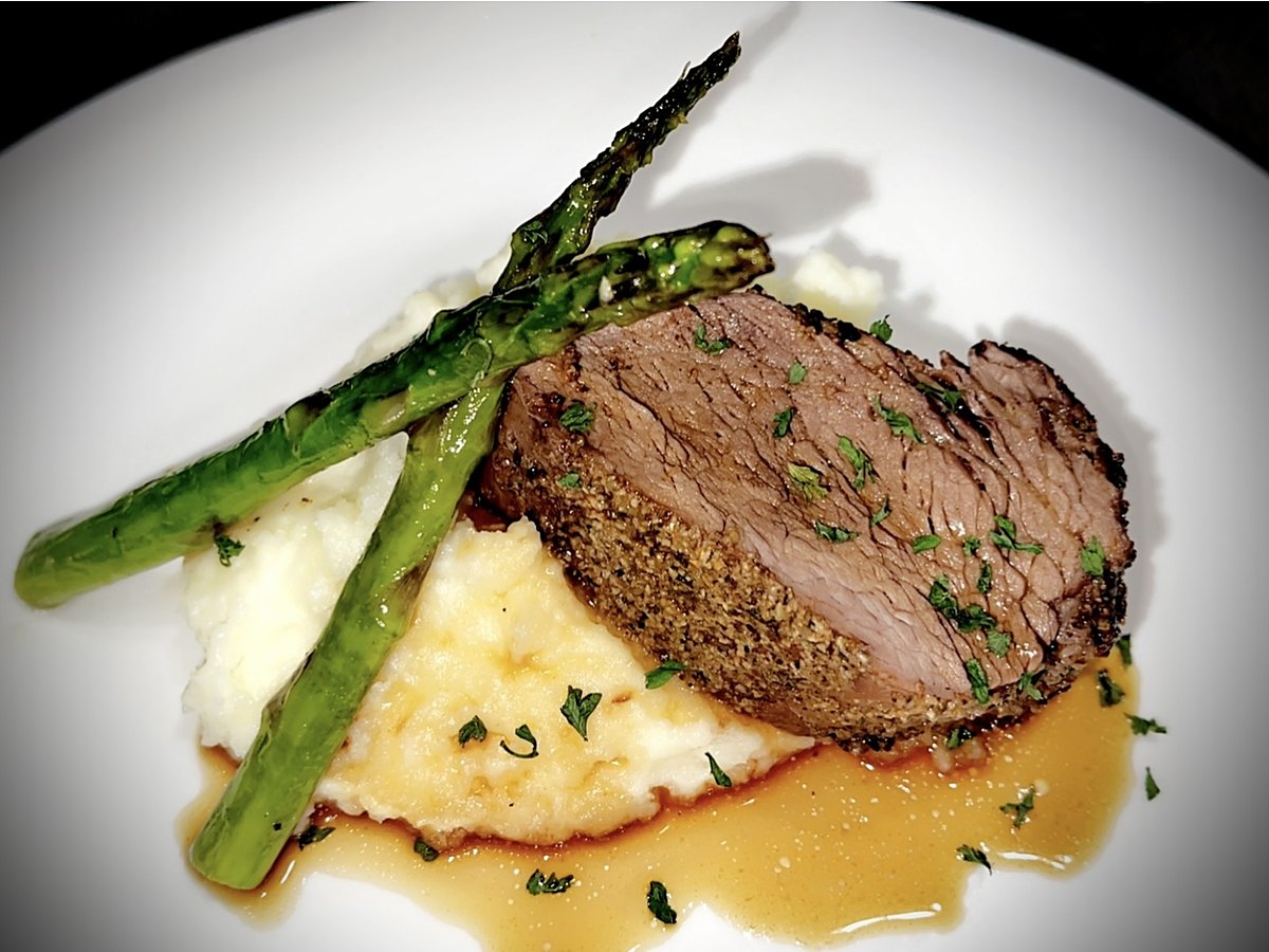 A plated dinner with asparagus over mashed potatoes