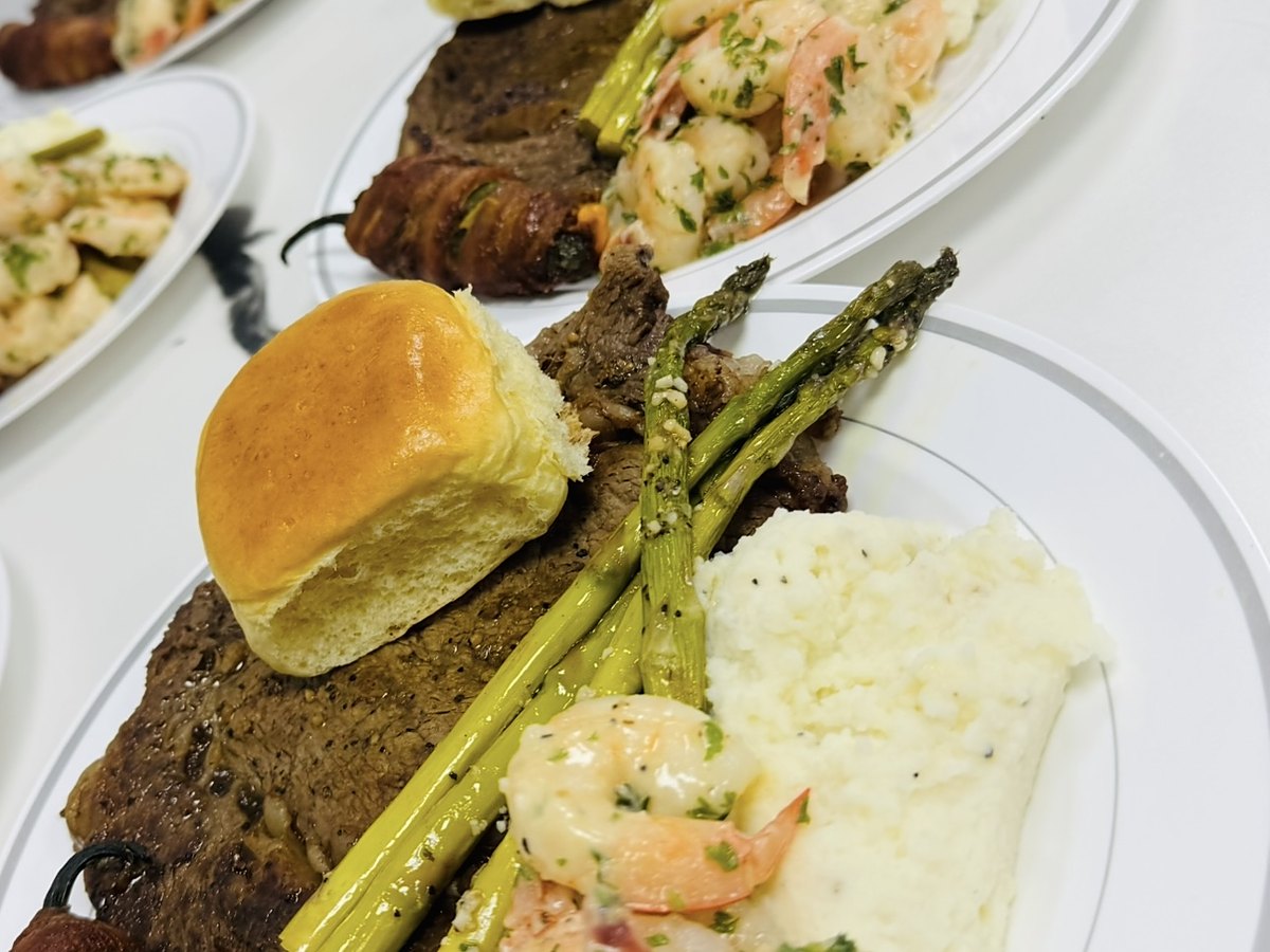 Plated steak and shrimp with asparagus, lined up for service